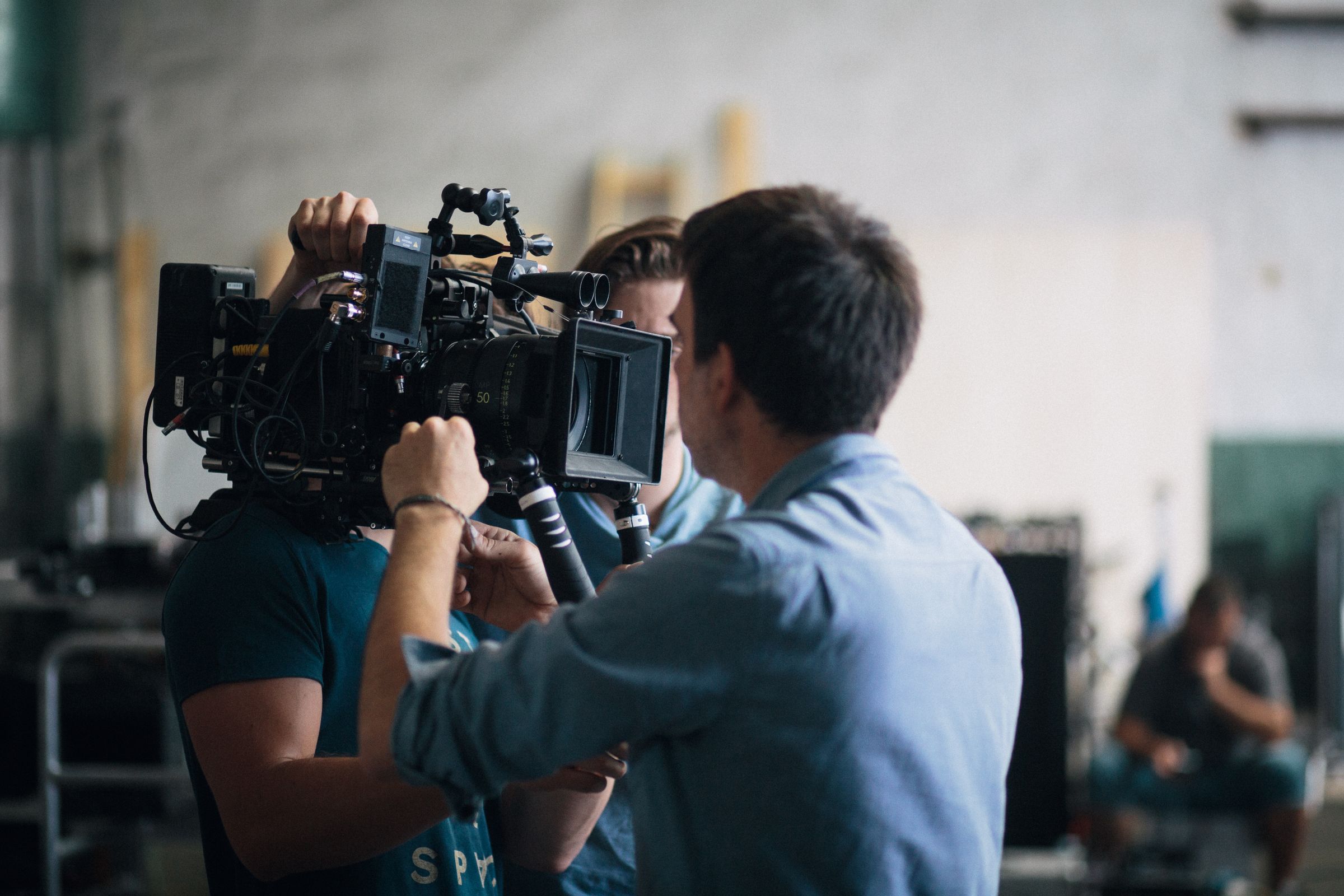 A crew adjusting a video camera on an indoor set.