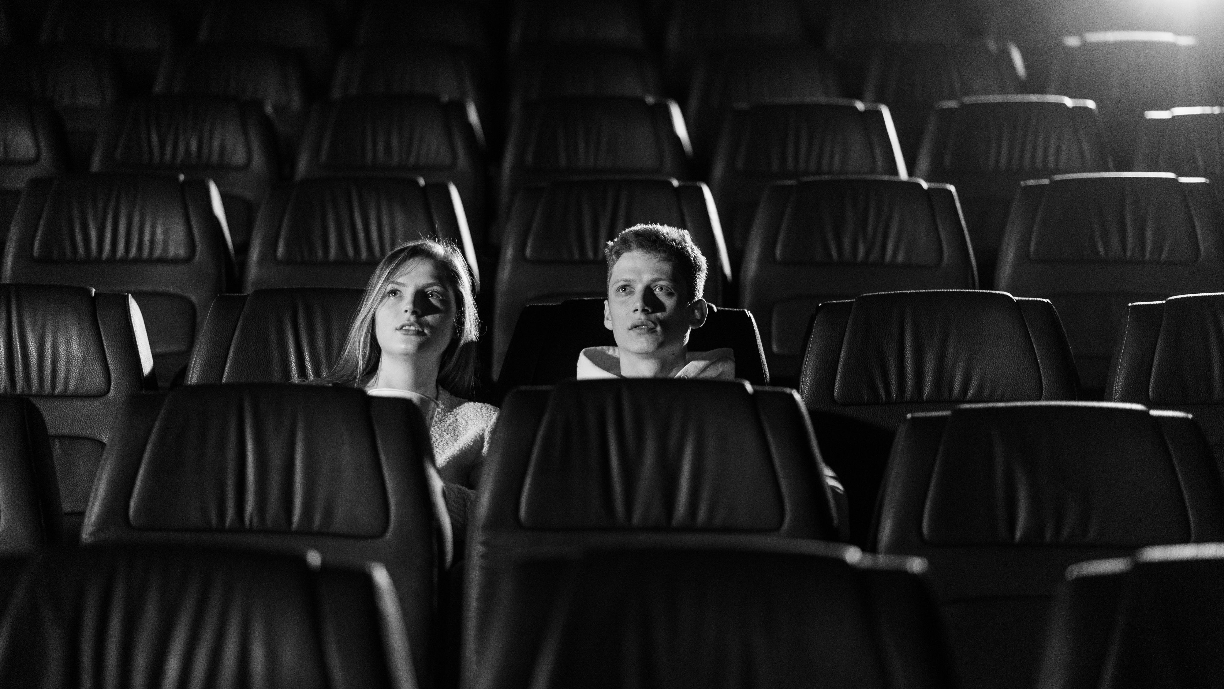Two people alone in a dark cinema, lit by the screen.